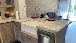 A modern kitchen with a built-in dishwasher, granite countertops, and wooden cabinetry. - Dazzling Waikiki Apt Sleeps 7-excellent A/C & PARKING included (Honolulu)