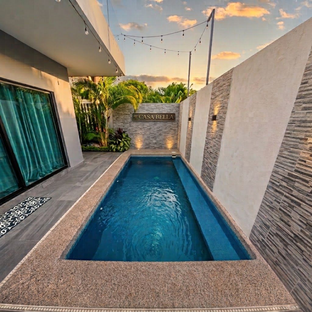 A modern swimming pool with a stone wall and a sign that reads 'CASA BELLA'.