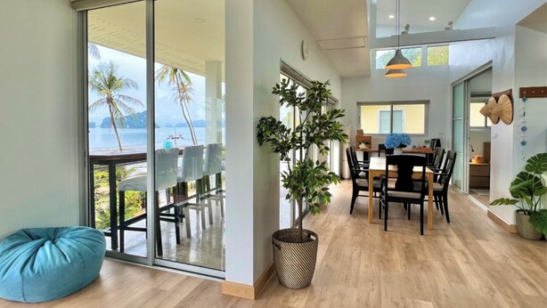 Un intérieur moderne comprenant un coin repas, une grande porte-fenêtre coulissante donnant sur un balcon et une vue sur la mer.