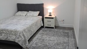 A bedroom with a bed, bedside table, lamp, and rug.