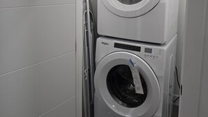 A compact laundry room with two stacked Whirlpool washing machines.
