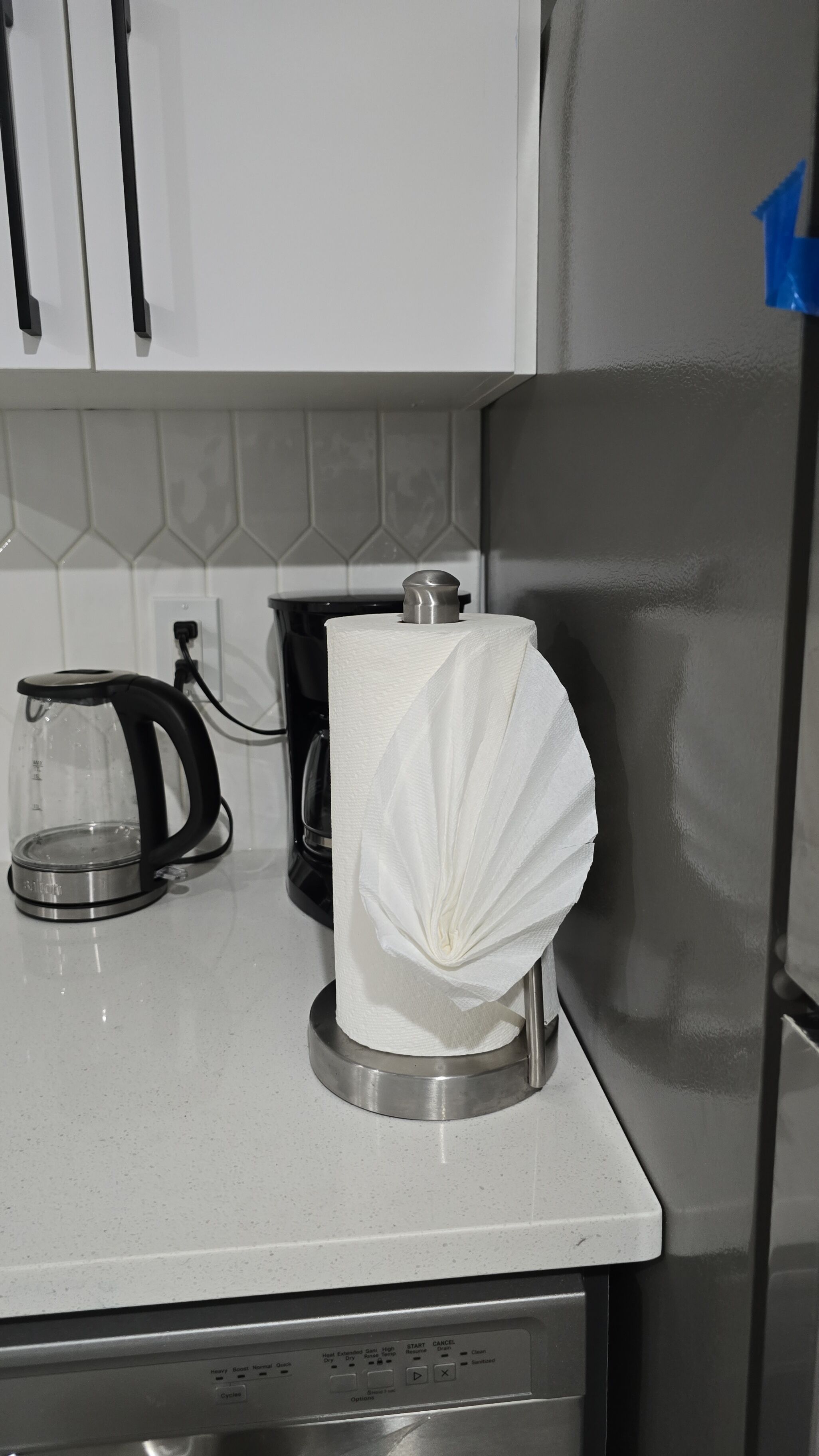 A kitchen with a coffee maker, a paper towel holder, and a dishwasher.