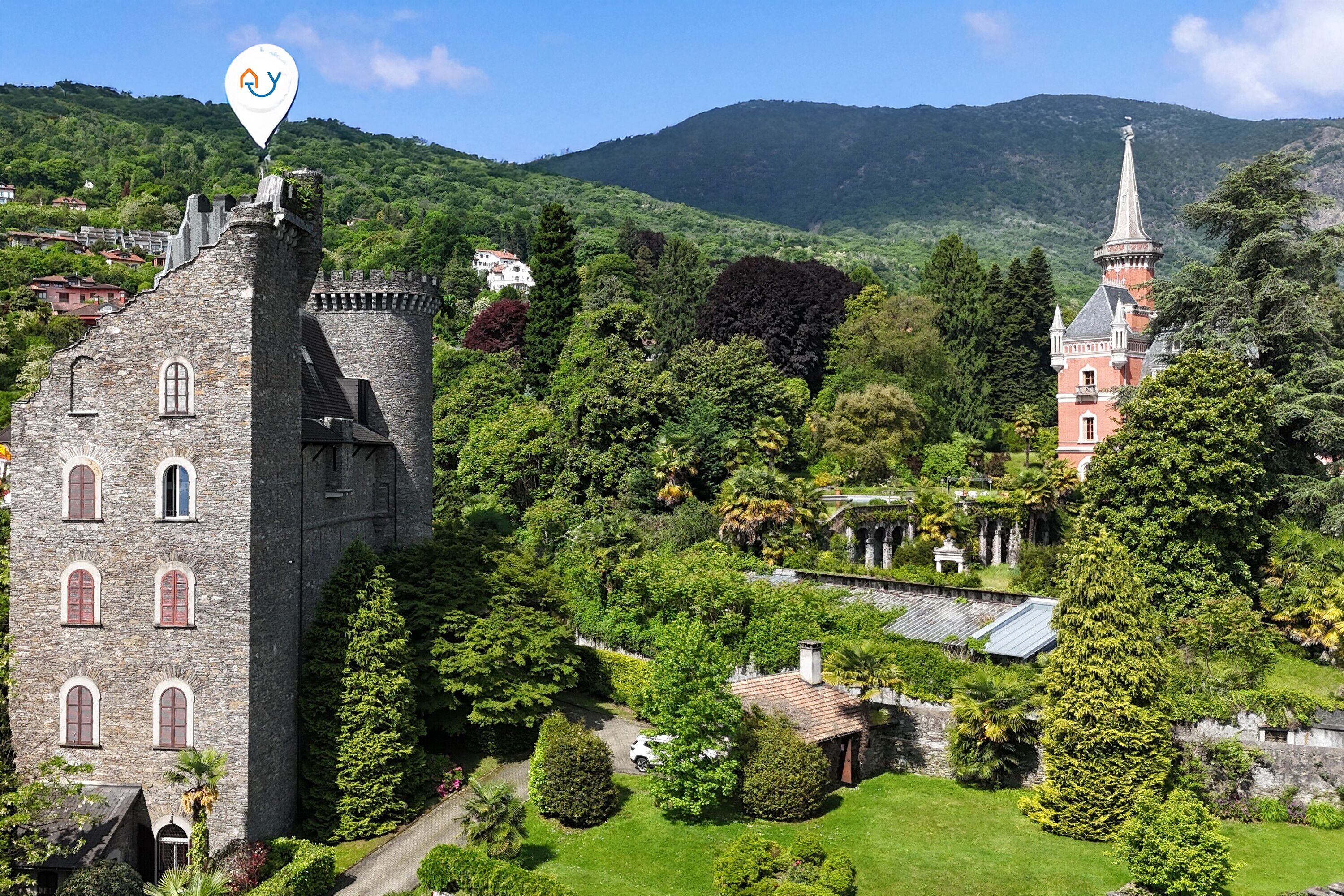 A castle with a tower, surrounded by lush greenery and a church with a spire.