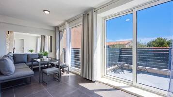 A modern apartment with a balcony, a sofa, a dining table, and a view of the city.