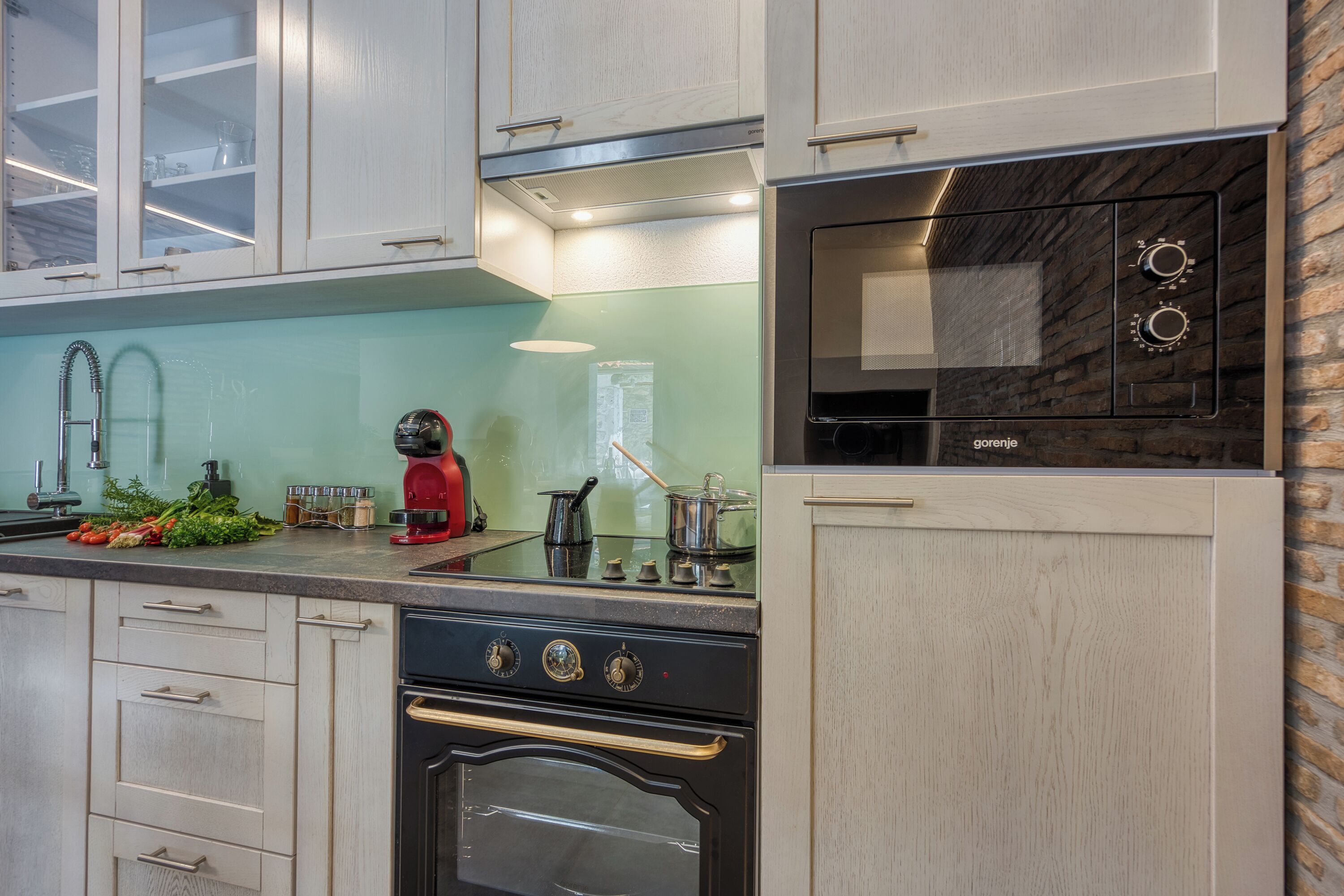 A modern kitchen with white cabinetry, a stainless steel stove, and a built-in microwave.