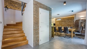 A modern interior with a wooden staircase, a dining area with chairs and a table, and a kitchen visible in the background. - Stone Villa Galant with Pool (Lanisce)