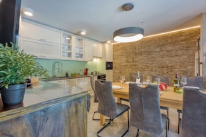 Una cucina moderna con mobili bianchi, un'isola in legno e una parete decorata con mattoni.