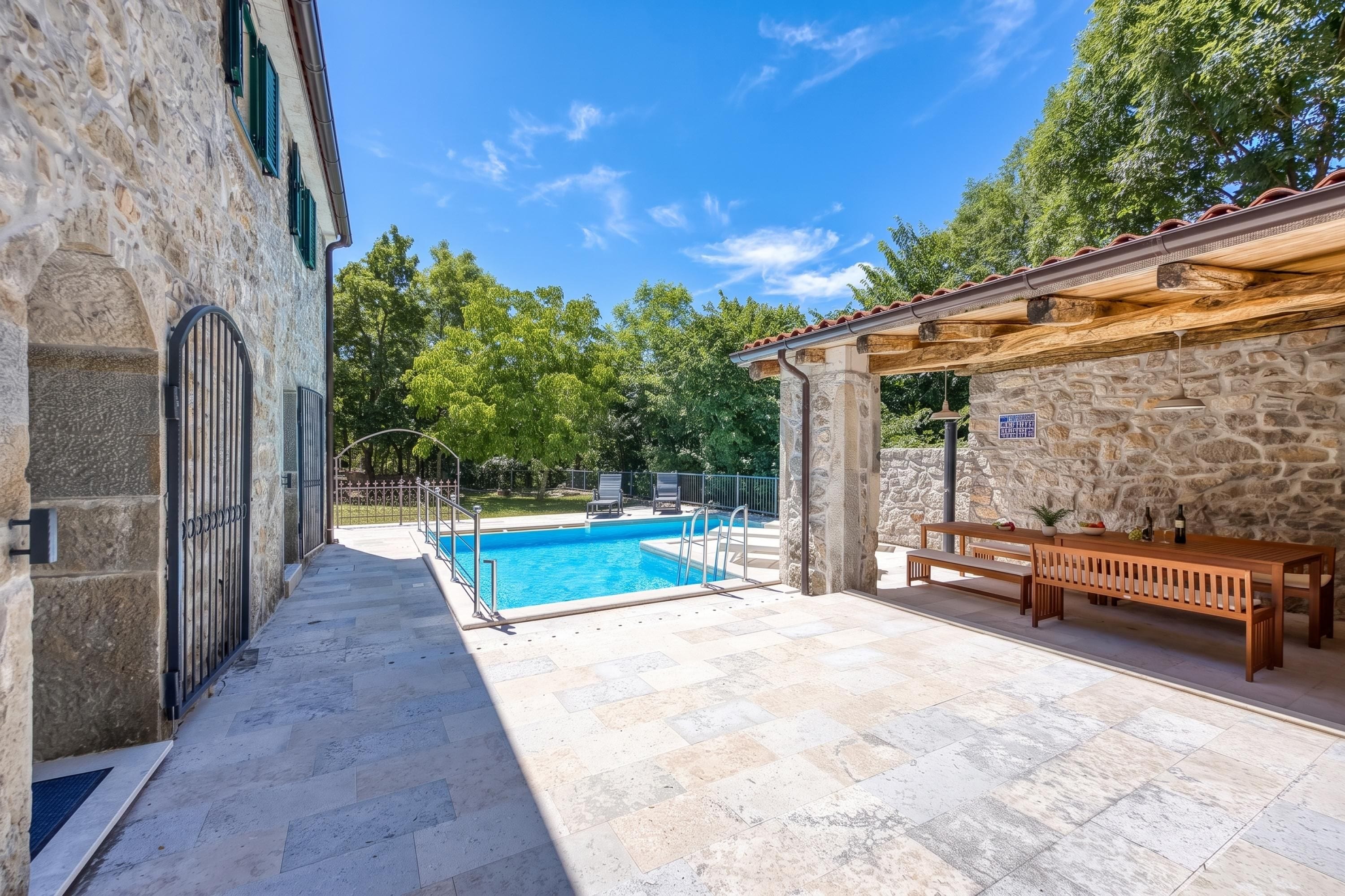 A stone building with a swimming pool, outdoor seating, and a covered area.