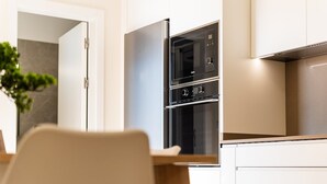 A modern kitchen with a stainless steel refrigerator, double oven, and white cabinetry.
