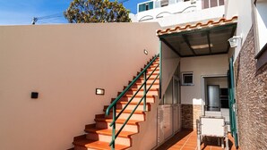 A staircase leading to a covered outdoor area with a tiled floor and a small table.