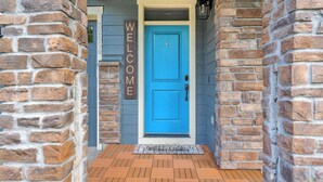 Una porta blu con un cartello 'WELCOME', un muro in mattoni e un pavimento in legno.