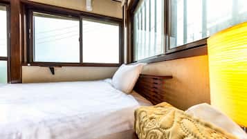 A bed with a wooden headboard, a window with blinds, and a yellow lamp.