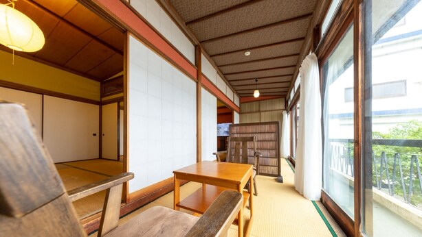 A traditional Japanese room with tatami flooring, a wooden table, and a view of the outside. - Azamian Atami (Atami)