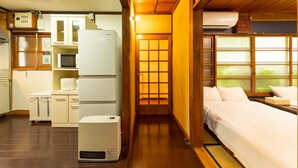 A compact hotel room with a kitchenette, a bed, and a view through a shoji screen. - Azamian Atami (Atami)