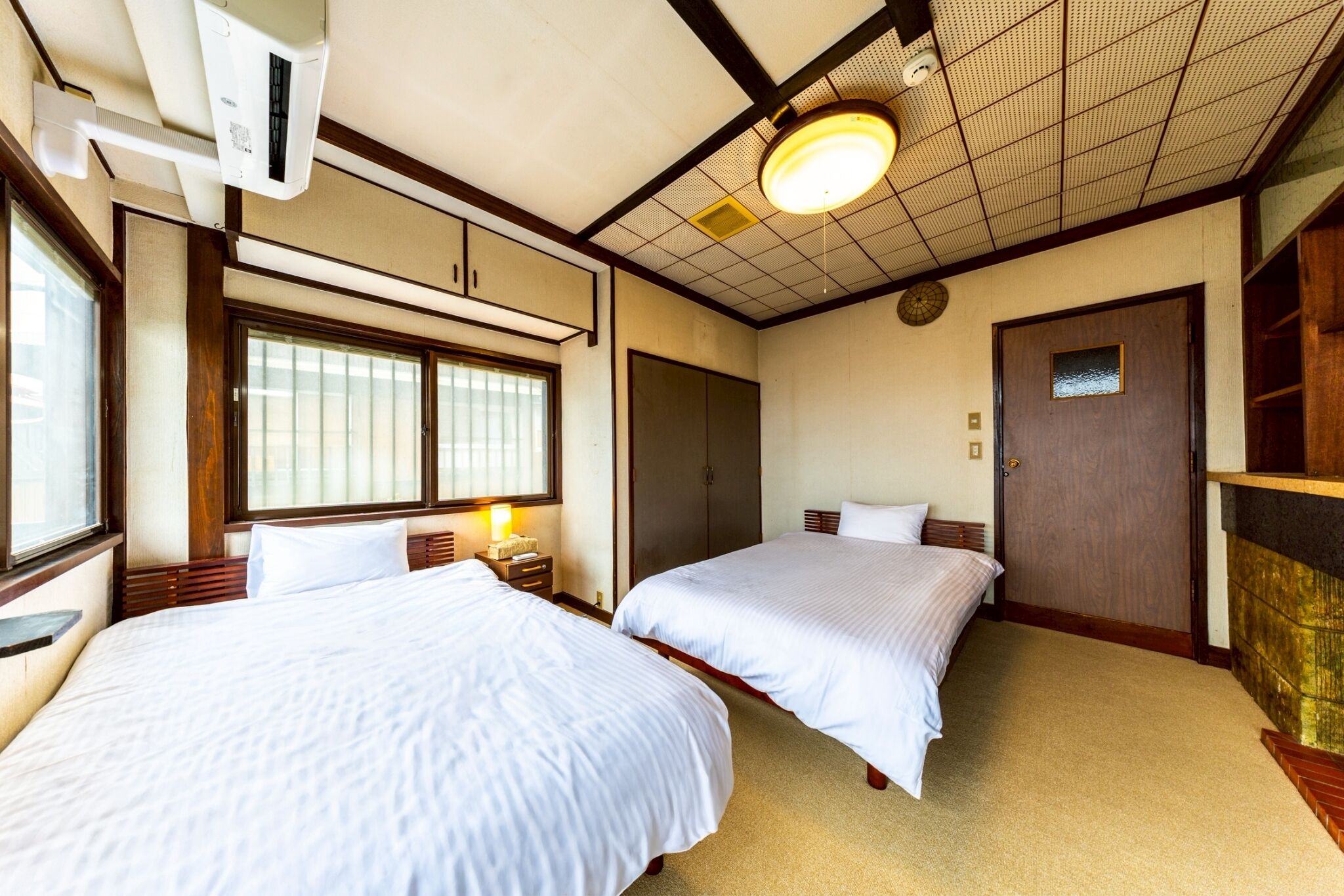 Habitación de hotel con dos camas, una ventana, una puerta y un ventilador de techo.