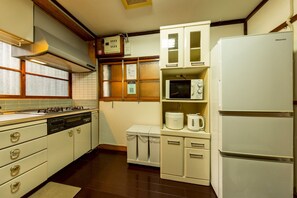 A compact kitchen with a gas stove, a microwave, a refrigerator, and a sink. - Azamian Atami (Atami)