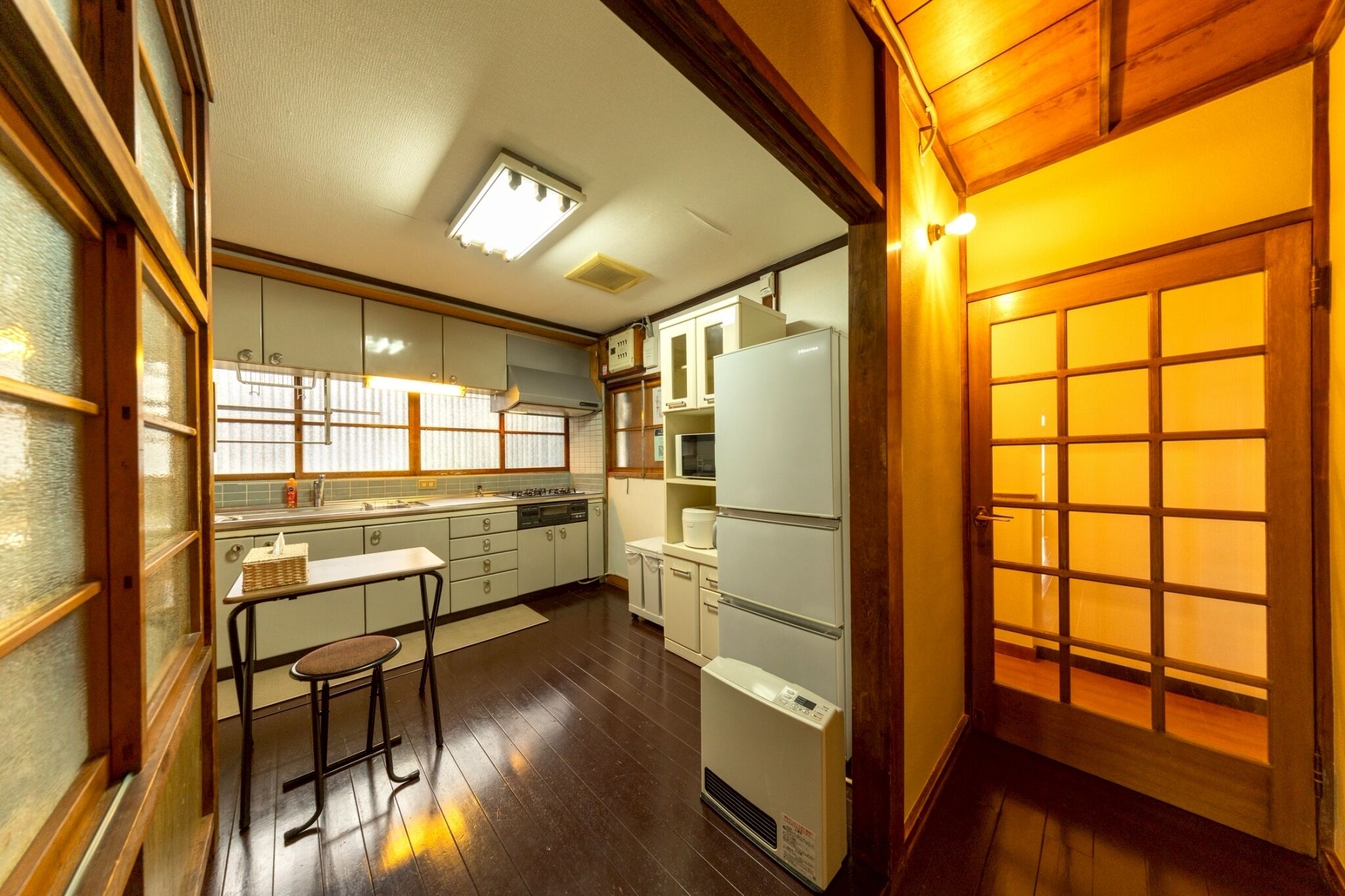 A compact kitchen with a refrigerator, stove, and bar stools.