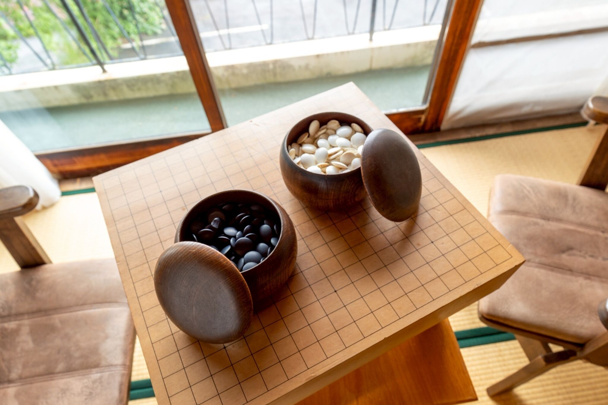 A wooden table with two bowls containing beans, placed on a grid-patterned mat.