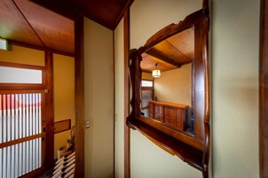 A traditional Japanese interior with a wooden door, a mirror, and a hanging basket.