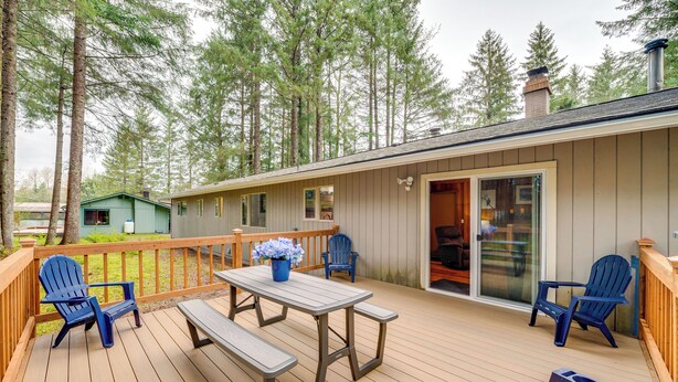 A wooden deck with a picnic table and blue chairs, surrounded by tall trees. - 3 Miles to the Mendenhall Glacier (Juneau)