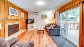 A living room with wooden walls, a fireplace, a sofa, a coffee table, and a television. - 3 Miles to the Mendenhall Glacier (Juneau)