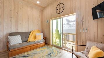 Un intérieur en bois comprenant un canapé, un fauteuil, une horloge et un téléviseur.