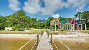 A wooden pier leading to a series of elevated houses with multiple levels and balconies.
