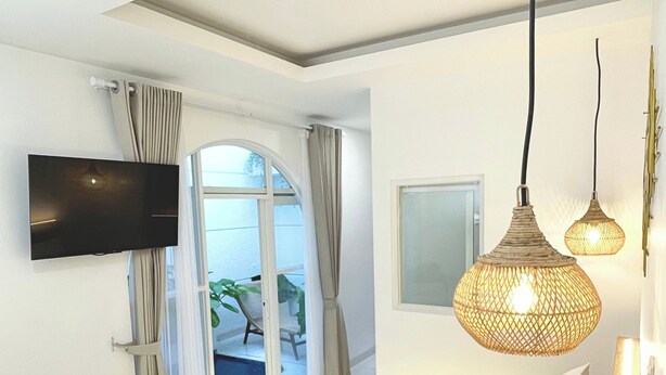 Een slaapkamer met een bed, een aan de muur bevestigde televisie en een raam met gordijnen.