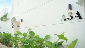 Een wit gebouw met het nummer 'A3A' en een klein plantje ervoor.
