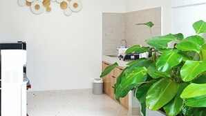 Een moderne keuken met een witte spatwand, een houten plafond en een grote groene plant.