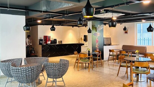 A modern cafe with a bar area, seating arrangements, and pendant lighting. - Wildwings premium hotel (Hyderabad)