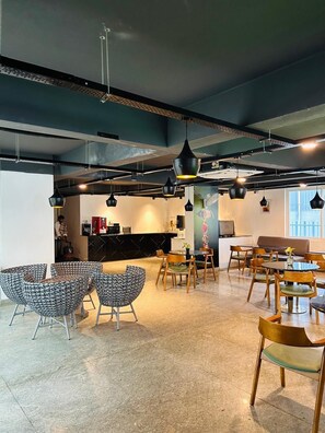 A modern cafe with a bar area, seating arrangements, and pendant lighting.