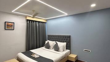 Un dormitorio moderno con una cama, mesitas de noche, un ventilador de techo y un cuadro en la pared.