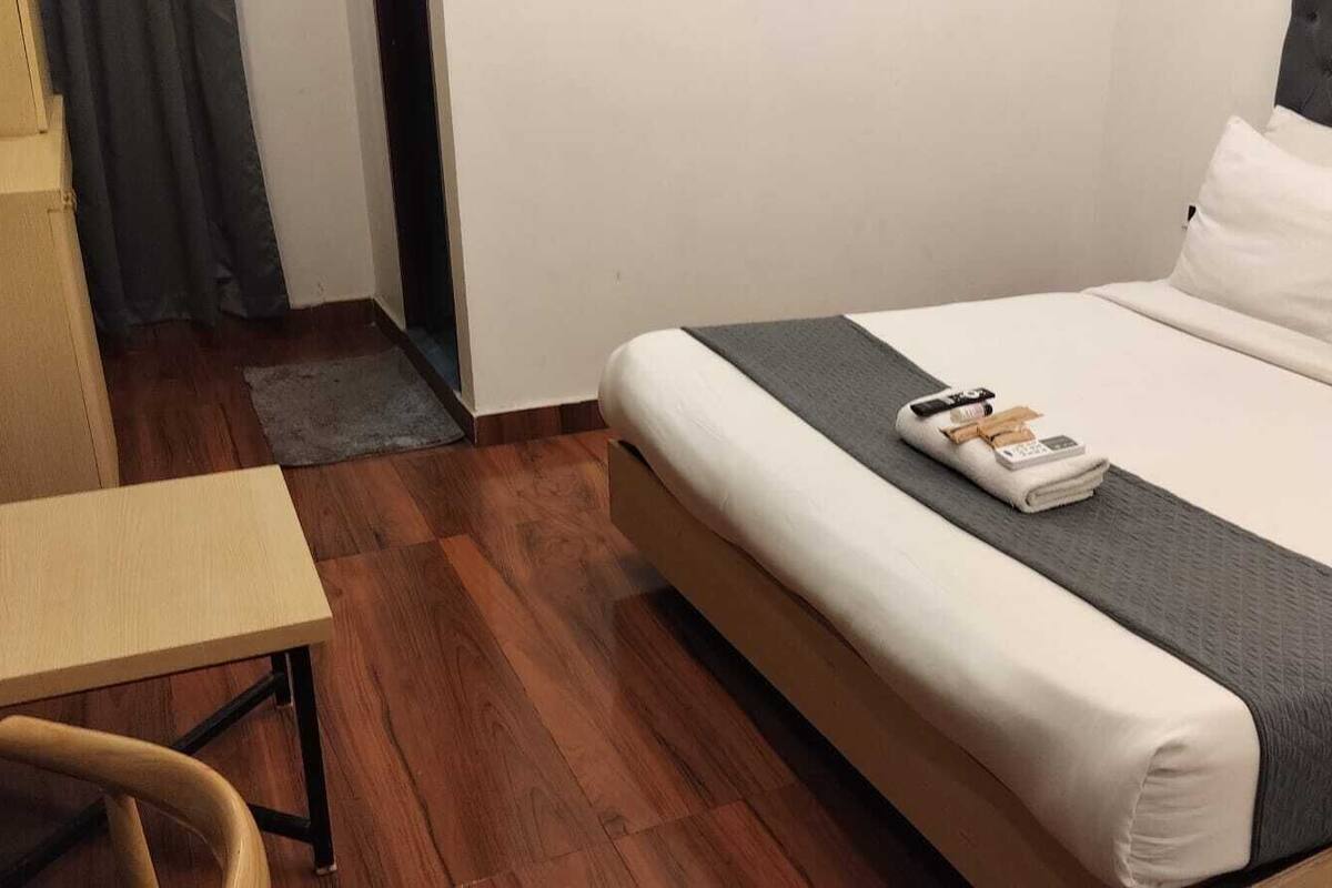 A hotel room with a bed, a desk, and a chair.
