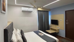 A modern hotel room with a bed, a ceiling fan, a flat-screen TV, and a desk. - Wildwings premium hotel (Hyderabad)