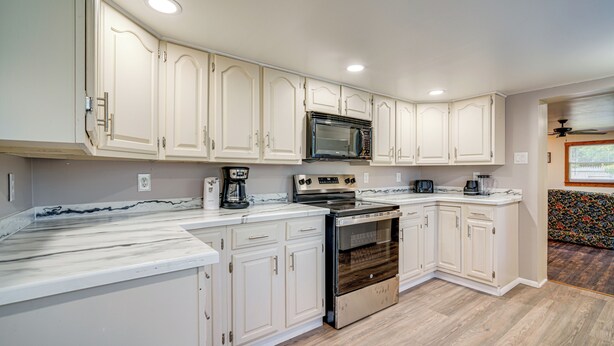 A kitchen with white cabinets, a built-in oven, a microwave, and a coffee maker.