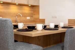 A modern kitchen with a wooden countertop, a sink, and a faucet. There are several white mugs and black plates on the counter. - Vacation apartment living on the Lofer (Reit im Winkl)