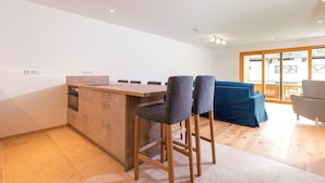 Une cuisine moderne avec un plan de travail en bois, deux tabourets de bar et une table à manger.