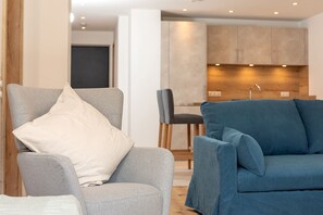 Un salon moderne avec un fauteuil gris et un canapé bleu, tous deux agrémentés de coussins.