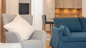 Un salon moderne avec un fauteuil gris et un canapé bleu, tous deux agrémentés de coussins.