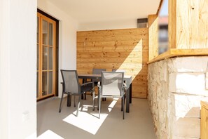 A dining area with a table and chairs, a wooden wall, and a stone wall.