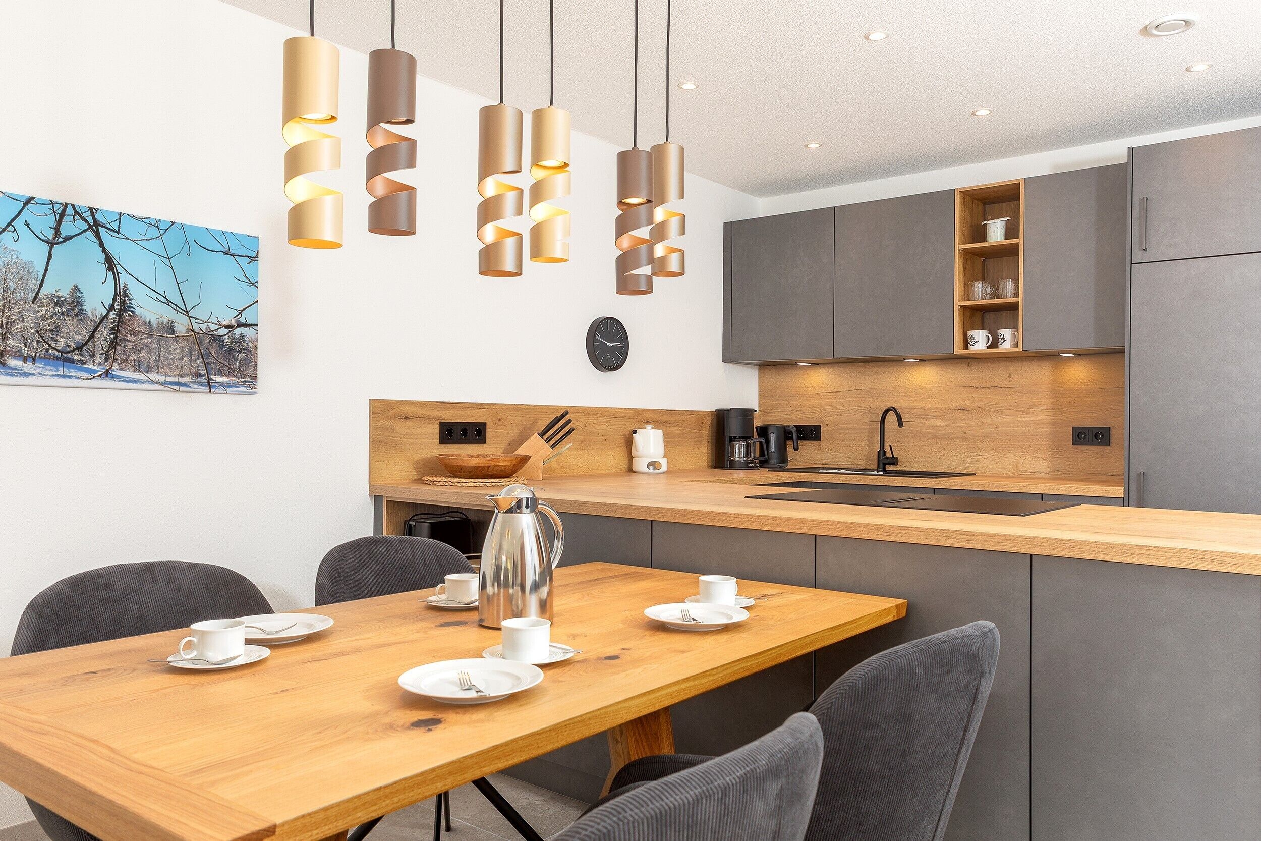 Una cocina moderna con una isla de madera, armarios grises y luces colgantes.