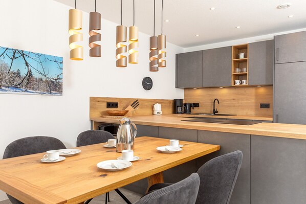 A modern kitchen with a wooden island, grey cabinets, and pendant lights.