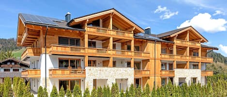 A multi-story wooden chalet with balconies, stone accents, and a well-maintained lawn.