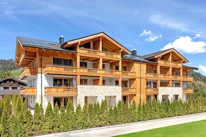 A multi-story wooden chalet with balconies, stone accents, and a well-maintained lawn.