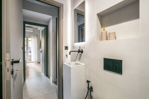 Un baño moderno con un lavamanos blanco, un espejo y un dispensador de toallas.