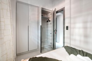 Un dormitorio con una cama, un armario y un vestidor abierto con perchero.