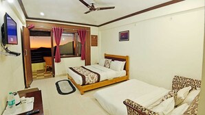 Ein Hotelzimmer mit Bett, Sofa, Fernseher, Deckenventilator und Blick ins Freie.