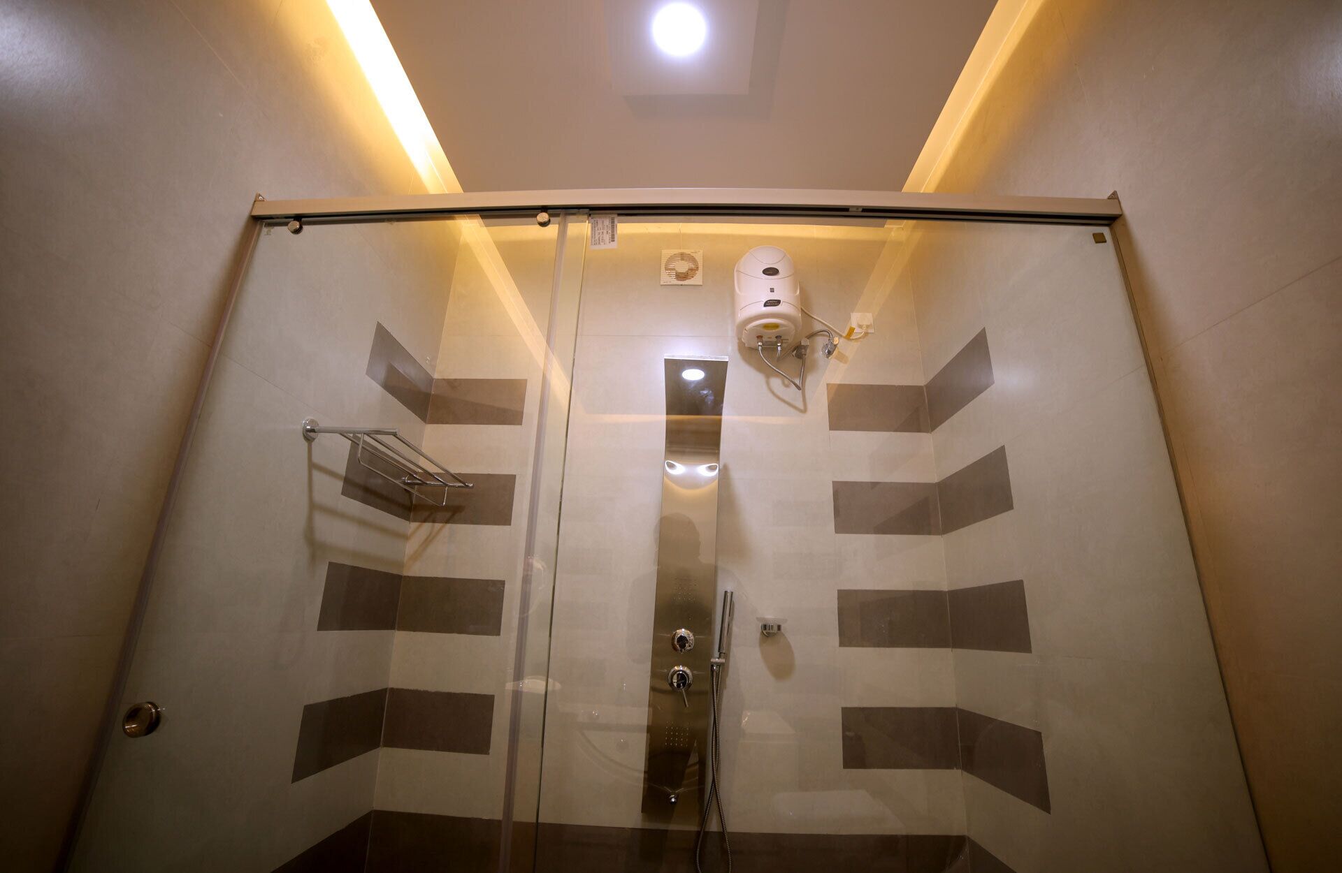 A glass-enclosed shower with a control panel and a hand dryer.