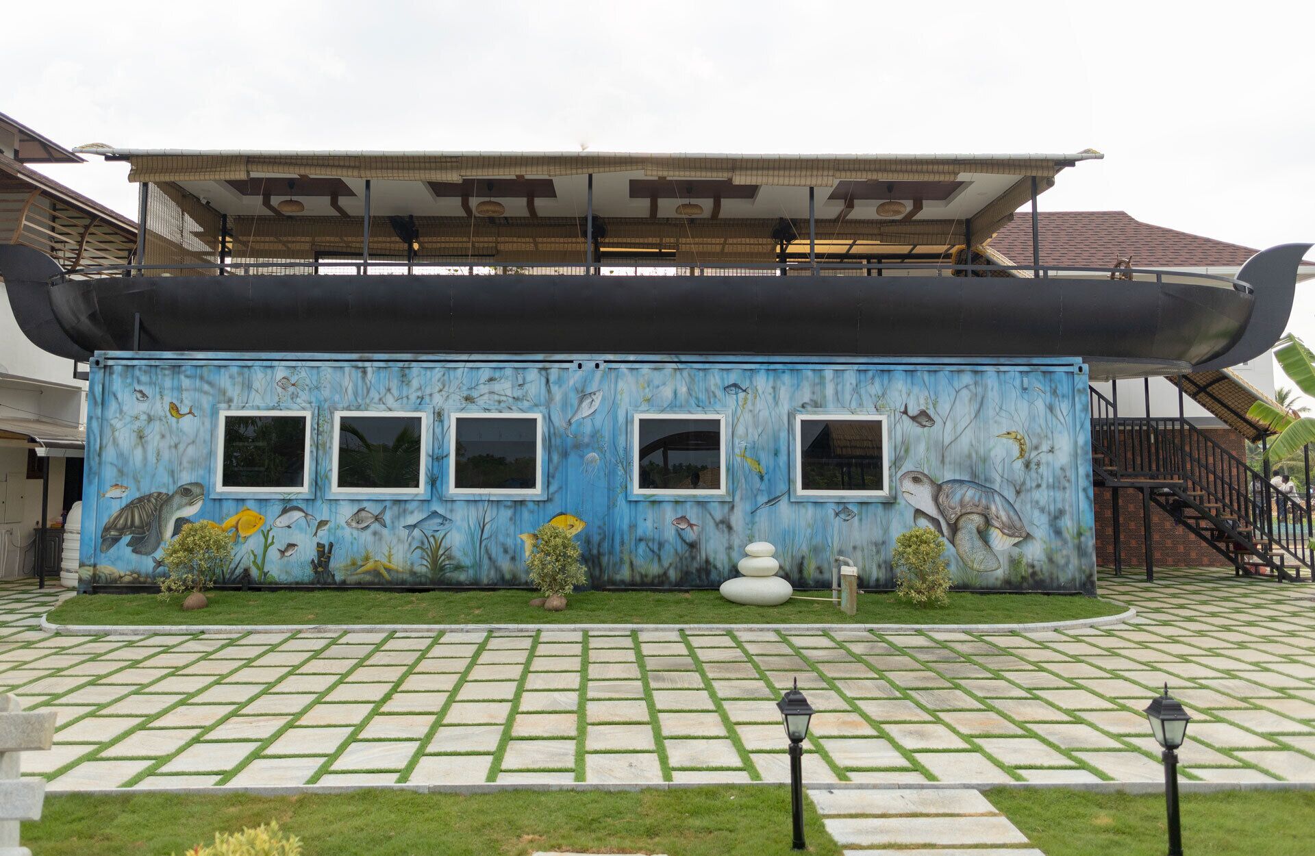 A building with a blue exterior, multiple windows, and a covered area with a roof.